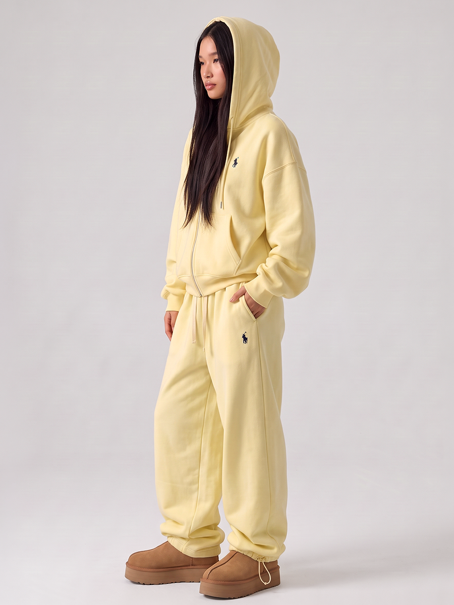 Woman wearing a pale yellow tracksuit with a zip hoodie and jogger pants