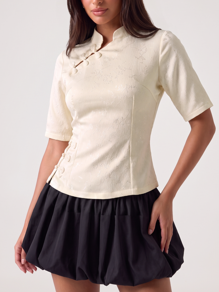 Woman wearing a cream blouse with a mandarin collar and asymmetric button front