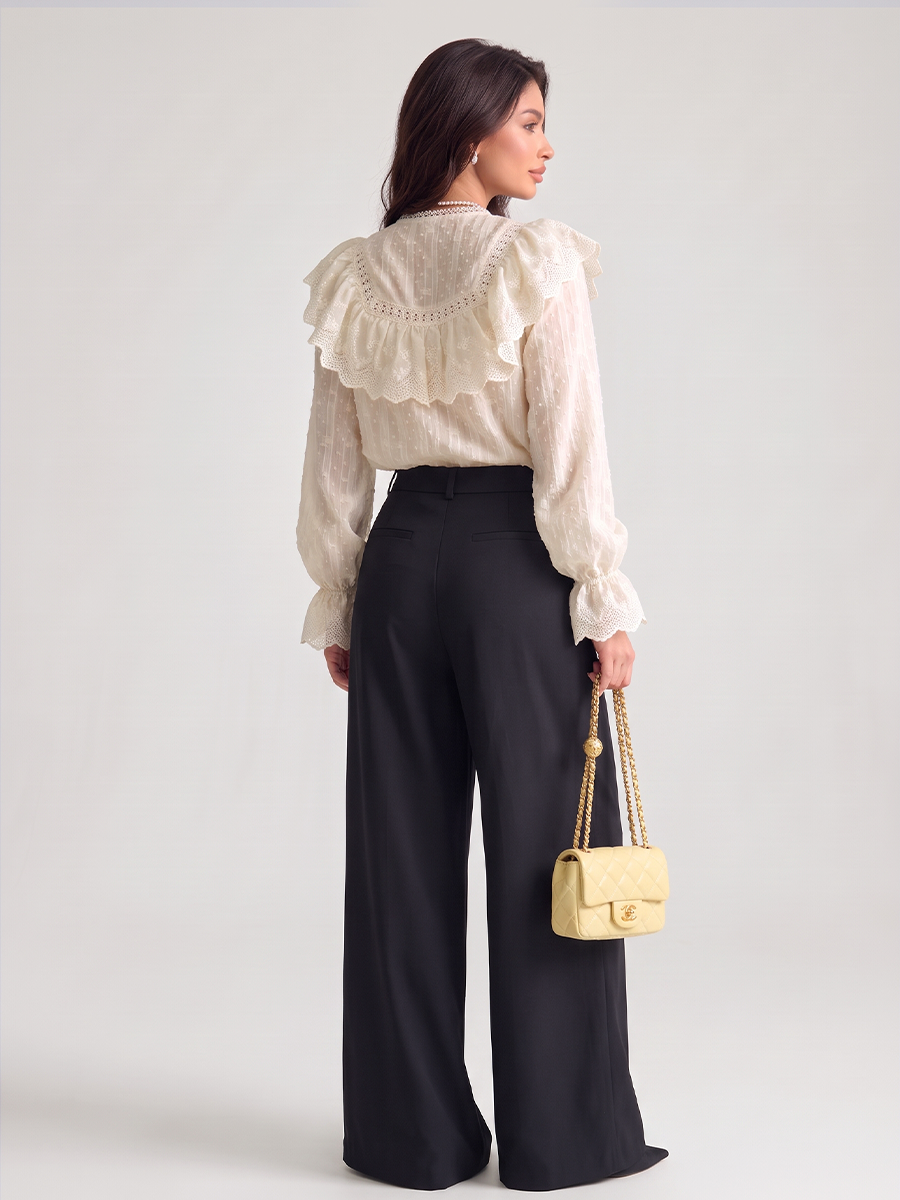 Woman wearing a white lace blouse with a ruffled yoke and long puff sleeves