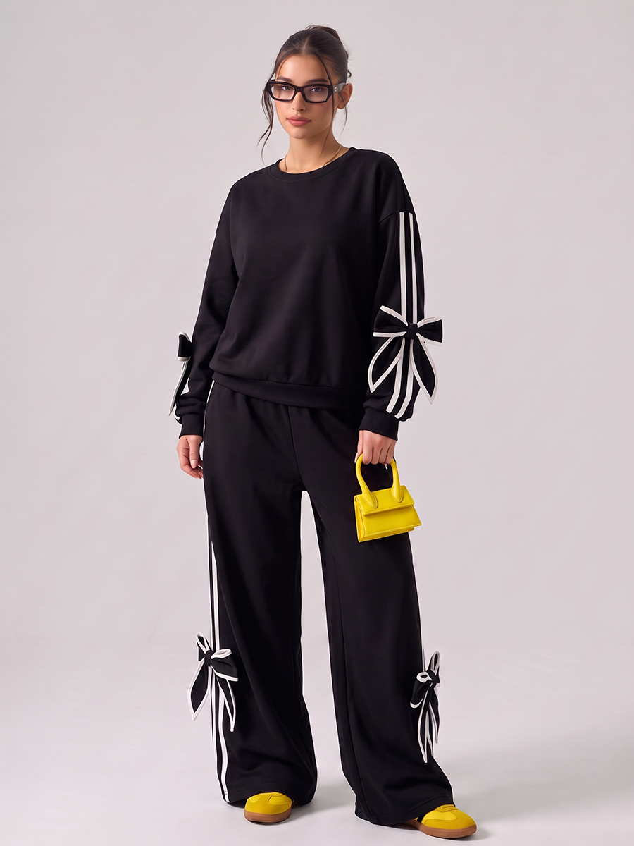 Woman wearing a black tracksuit with white bow details and side stripes