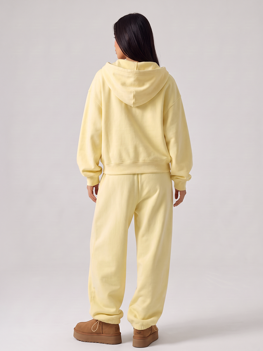 Woman wearing a pale yellow tracksuit with a zip hoodie and jogger pants