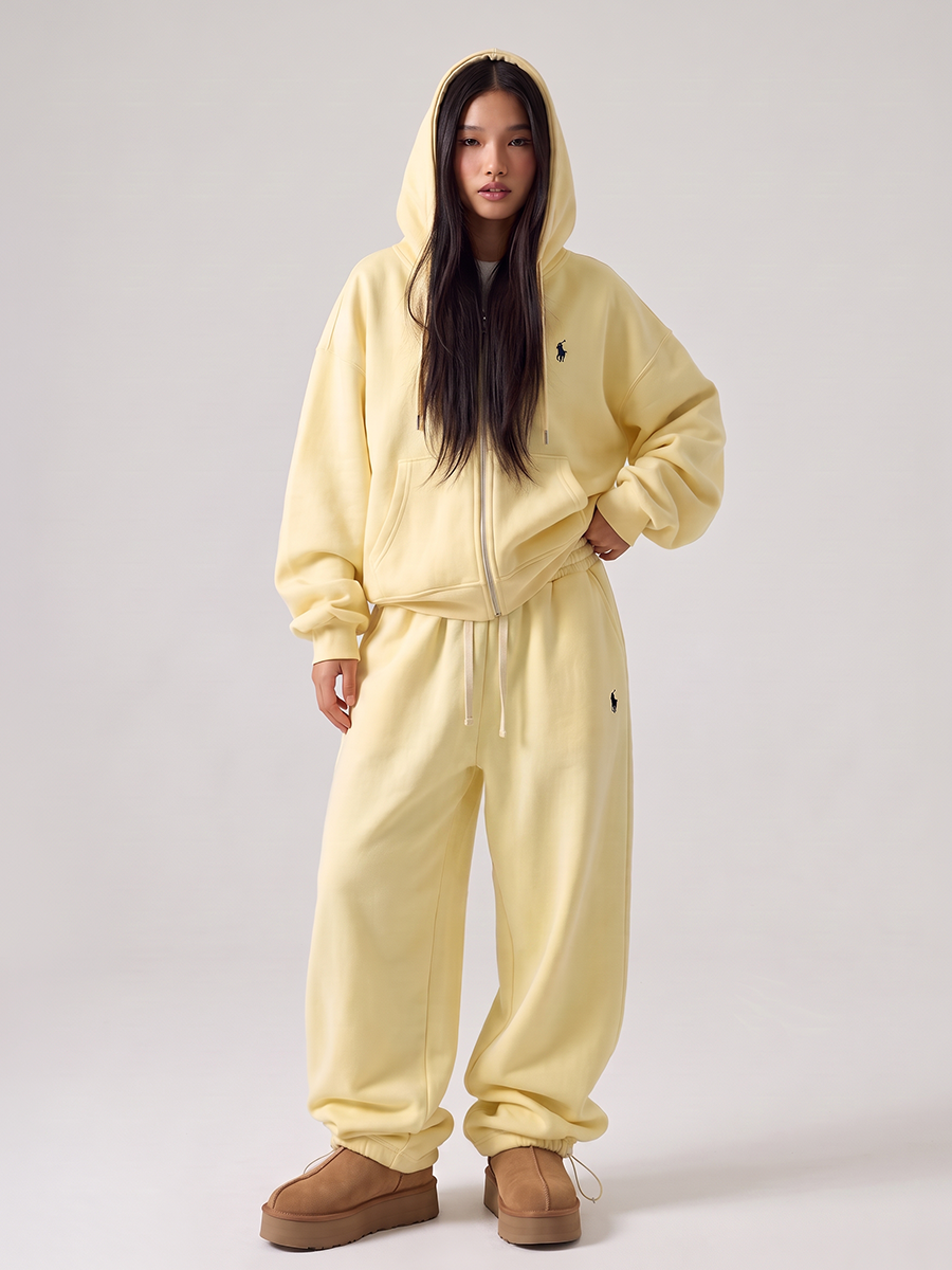 Woman wearing a pale yellow tracksuit with a zip hoodie and jogger pants