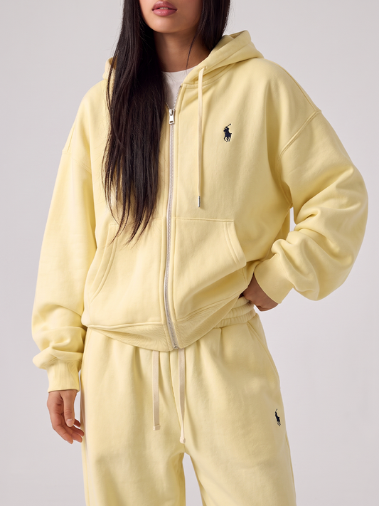 Woman wearing a pale yellow tracksuit with a zip hoodie and jogger pants