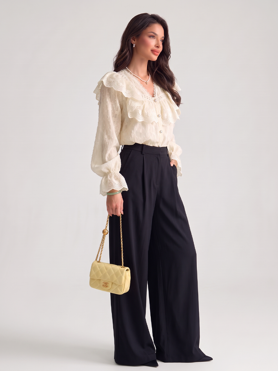 Woman wearing a white lace blouse with a ruffled yoke and long puff sleeves
